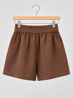 Brown linen-blend shorts with an elastic waistband and side pockets, displayed on a wooden hanger against a light grey background.