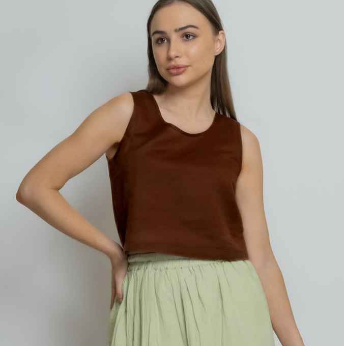 Woman wearing a brown top and light green skirt on a plain background